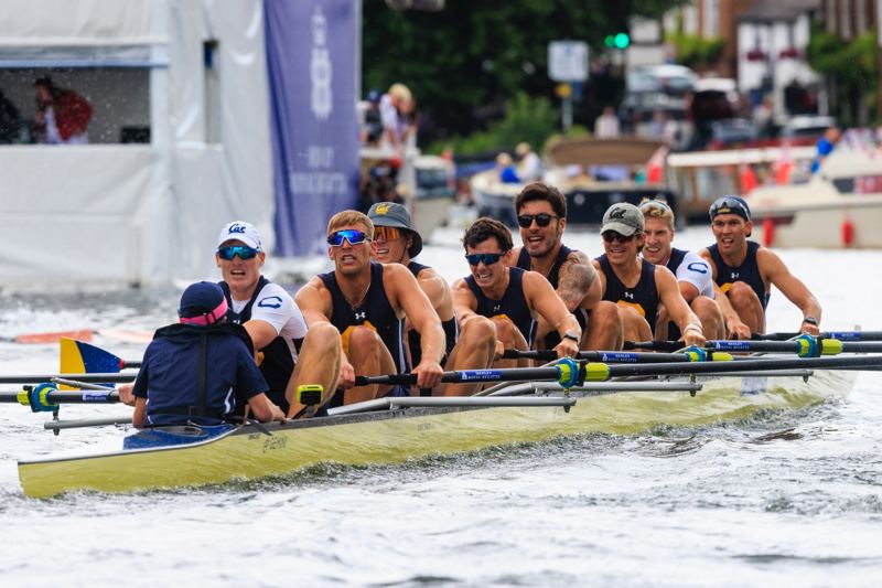 A collegiate eight racing past the regatta enclosures